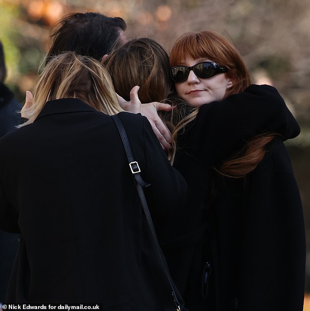 Singer Nicola Roberts, 39, hugs a fellow mourner before the funeral this afternoon.