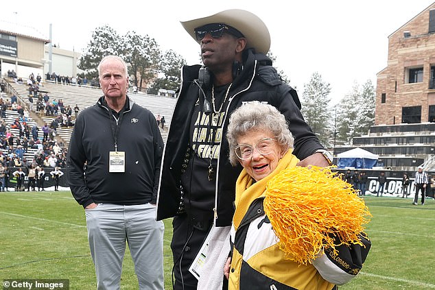 Colorado Buffaloes head coach Deion Sanders stands with fan Peggy Coppom, then 98, in 2022. On Tuesday, Coppom turned 100 in Boulder.