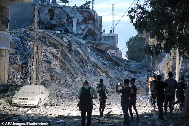 People walk on the rubble of a tower destroyed in an Israeli airstrike in Gaza City on Saturday.