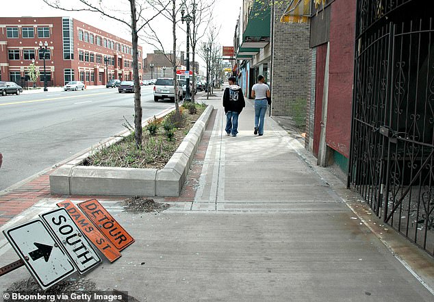 A fallen sign lies on the sidewalk as a couple walks down Broadway in Gary, Indiana, Thursday, April 20, 2006.
