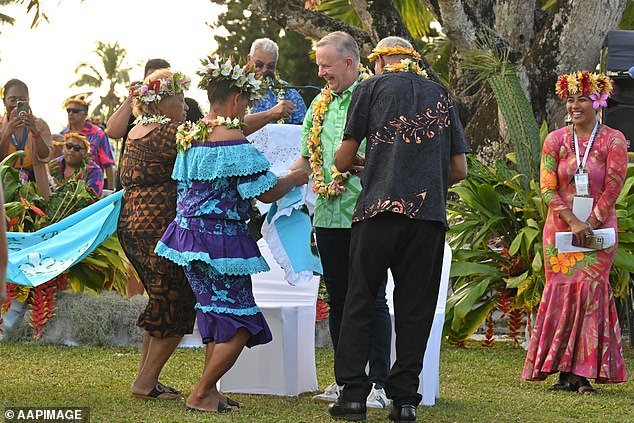 As his popularity plummeted in Australia, Anthony Albanese (in green shirt and garland) was posted to the Cook Islands.