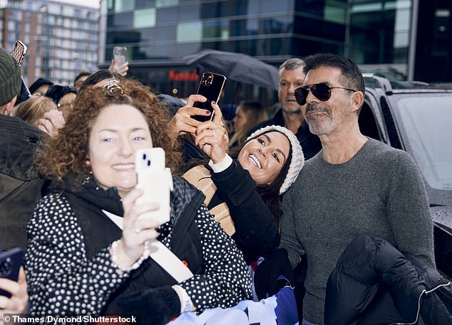 Simon stopped to take selfies with fans as they waited en masse.