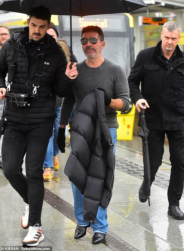 Meanwhile, frontman Simon Cowell, 64, arrived in his usual gray top and jeans while his assistant kept him dry under an umbrella.