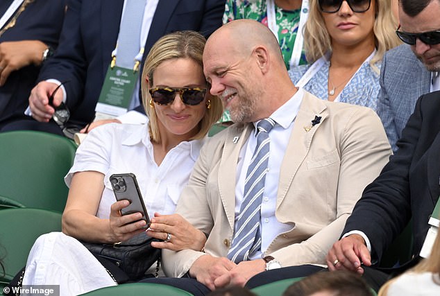 Zara Phillips and Mike Tindall smile as they look at their phones during the second day of Wimbledon last year.