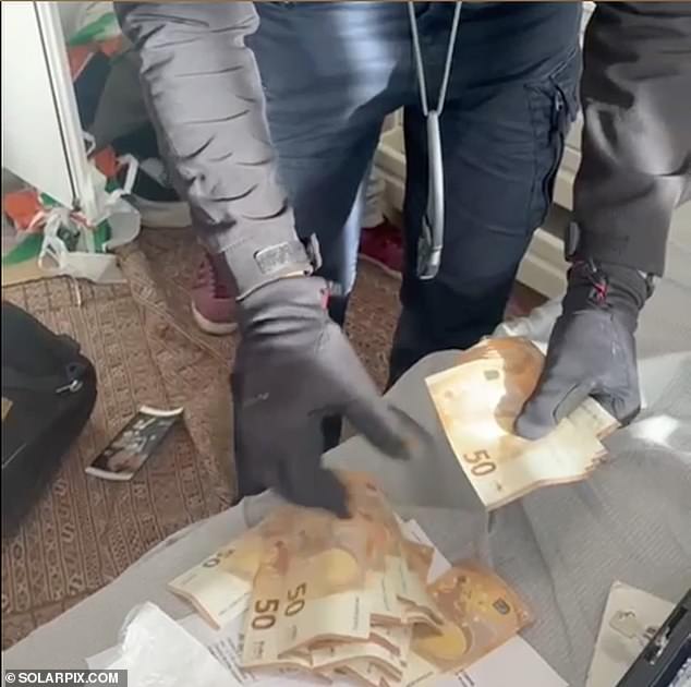 Detectives are seen counting a wad of 50 euro notes found inside the house.