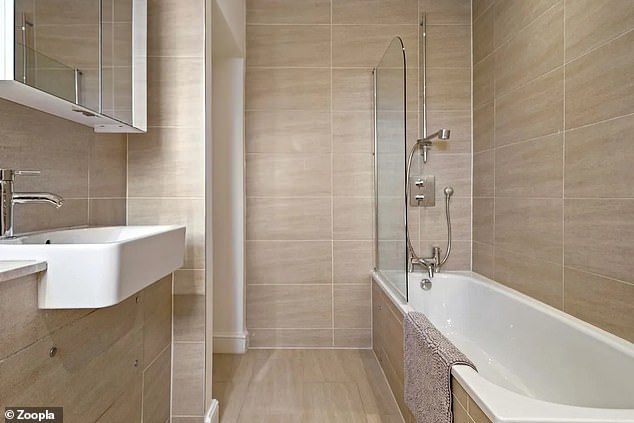 The modern bathroom has floor-to-ceiling tiles and a modern white suite.