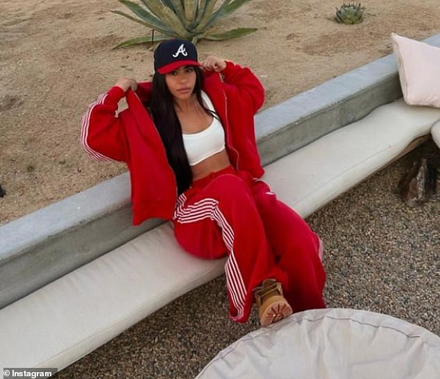 A sporty image of Gianna Gotti wearing a red tracksuit with a white crop top and a baseball cap.