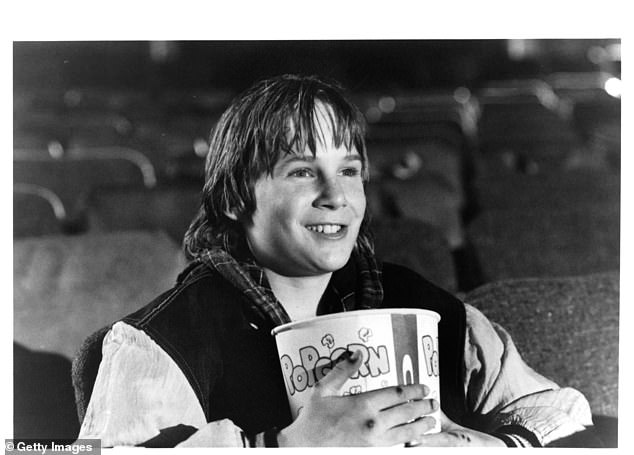 Austin O'Brien eating popcorn in the theater in a scene from the film Last Action Hero, 1993