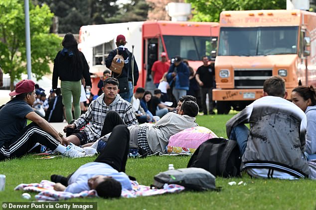 Migrants photographed waiting in a park in Denver, Colorado, in May 2023, one of the sites that will see a significant reduction in funding this year due to the border crisis.