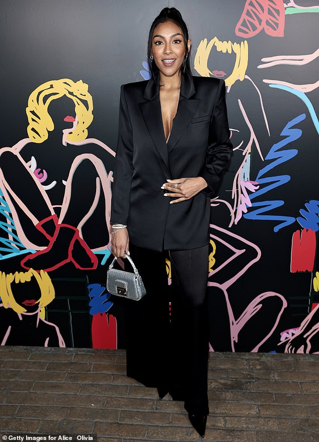 Tayshia Adams opted for a modern black pantsuit and accessorized it with a sleek silver bag.