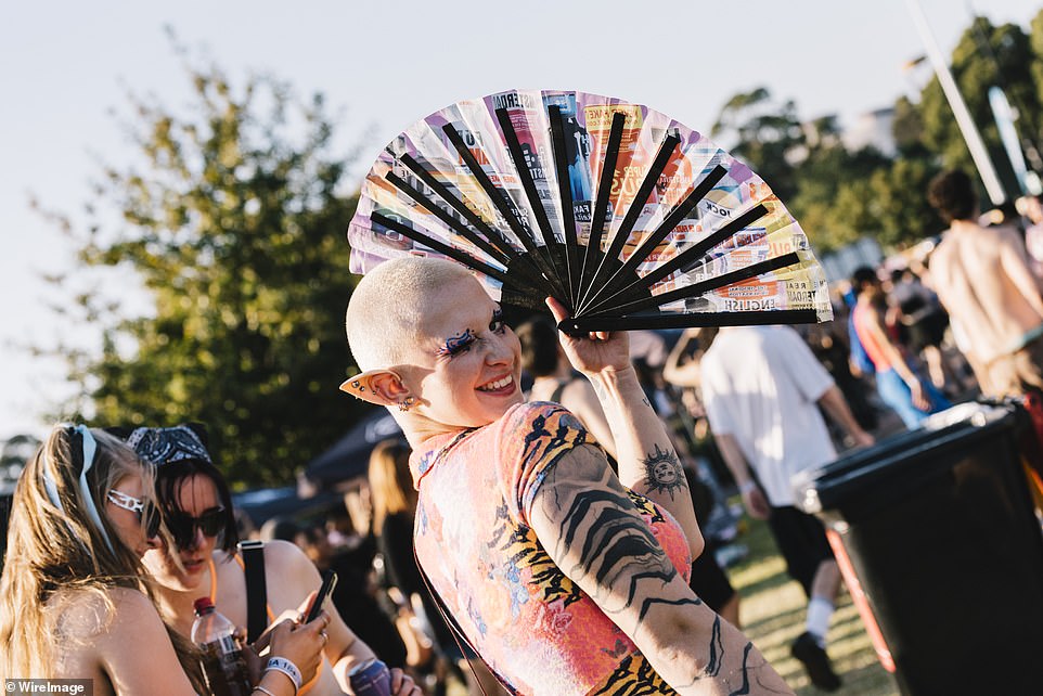 In the photo, a tattooed festival-goer accessorized her look with prosthetic elf ears, bright makeup and a handheld fan.