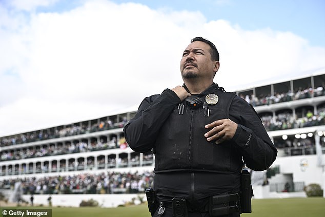 A police officer watches fans on the 16th green during Saturday's action at the Phoenix Open.