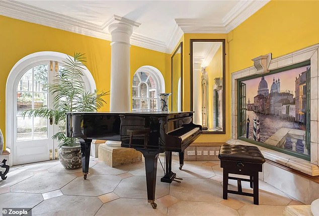 The large yellow reception room includes space for a grand piano and has a large mural of a city canal scene.