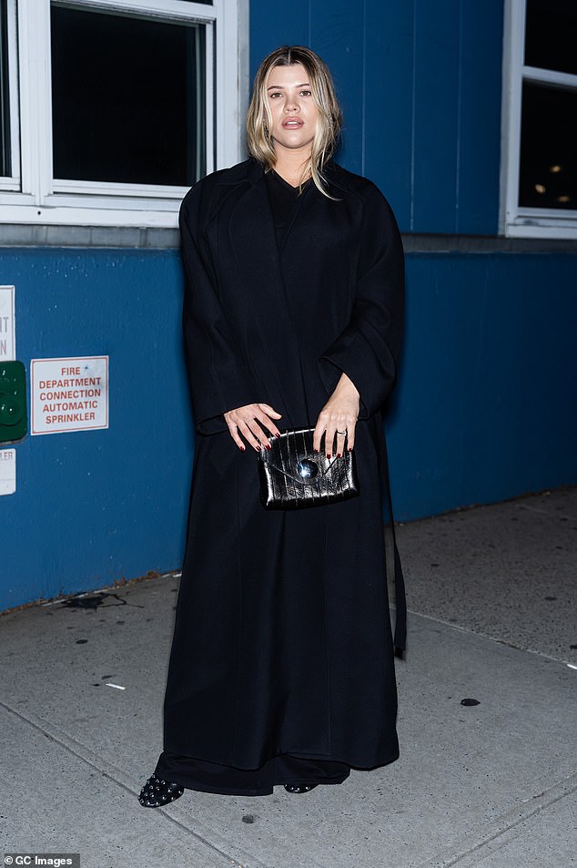 The mother-to-be, 25, stole the show as she cradled her baby bump in a chic black trench coat.