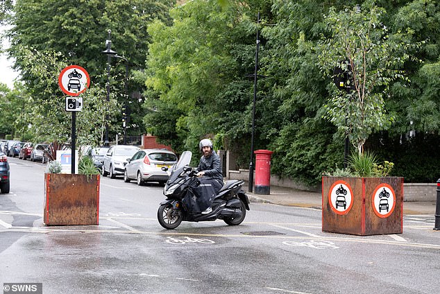 A motorcyclist appears next to planters on the LTN on Evering Road in Hackney, east London.