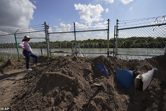 Magali Urbina stands near a gate on a pecan farm that has been demolished, locked and lined with concertina wire along the Rio Grande near Eagle Pass.