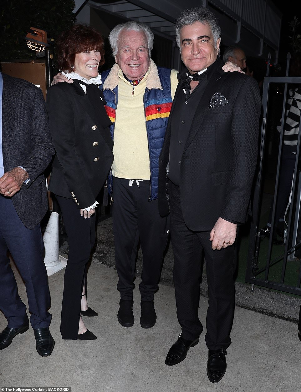 The star looked stylish in a pair of black pants and a pale yellow sweater with a multi-hued scarf. The Austin Powers franchise star stayed warm in the cold night air in a navy blue, rainbow-striped quilted vest (pictured with an unidentified friend)