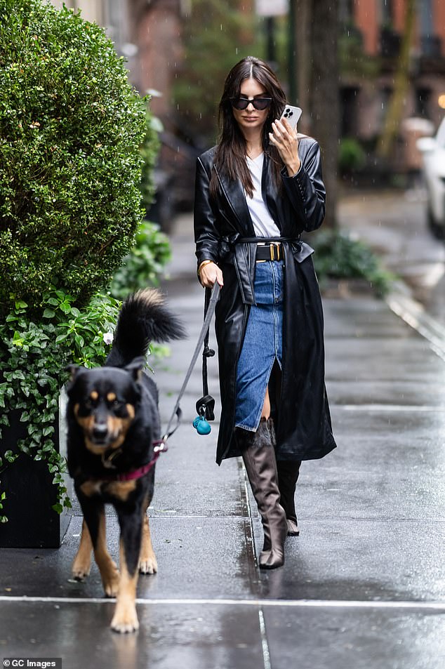 Emily Ratajkowski in a denim pencil skirt paired with a leather trench coat and knee-high boots