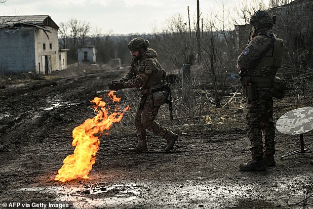 Ukrainian servicemen light a fire with gunpowder to warm themselves near the town of Bakhmut