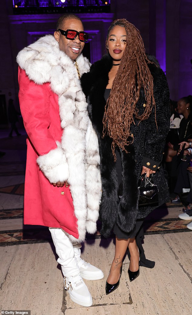 Rapper Busta Rhymes attended the event wearing a red coat with white and gray fur trim; Pictured with Cacie Smith.