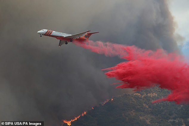 A firefighting aircraft is seen spraying the area with specially formulated fire retardants designed to smother sparks.
