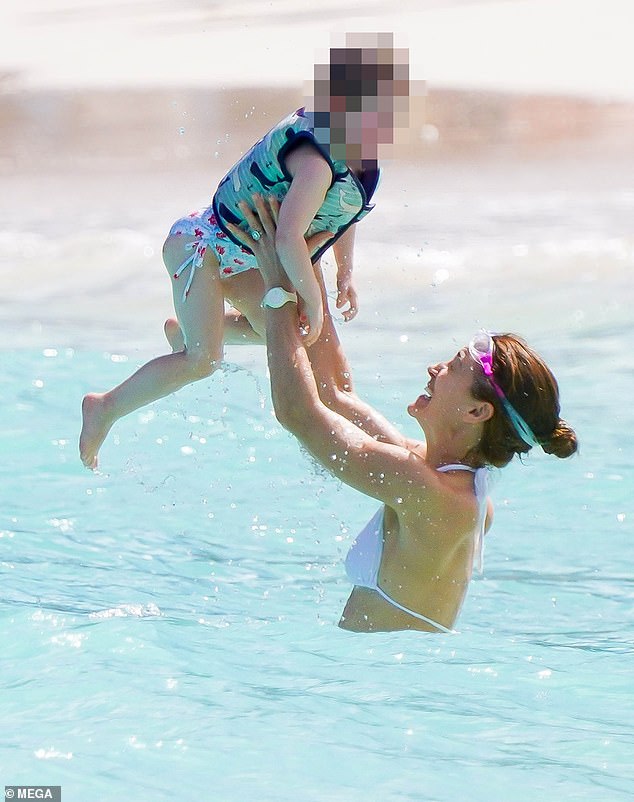 The mother of three was seen playing happily with her daughter in the ocean during the family vacation.