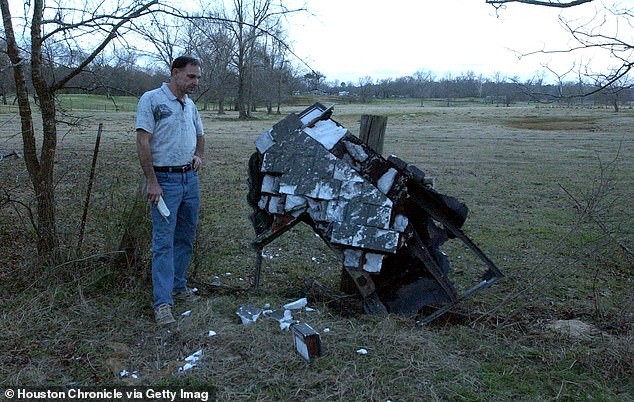 Mac Powell stands next to what he believes is the suspected damaged left wing of the downed space shuttle Columbia, on his property in Nacogdoches County, Texas, in 2003.