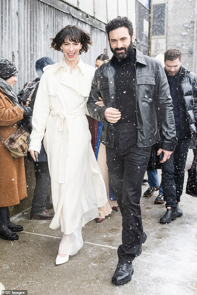 Actress Rebecca Hall wore a long white trench coat and attended the show arm in arm with actor Morgan Spector.