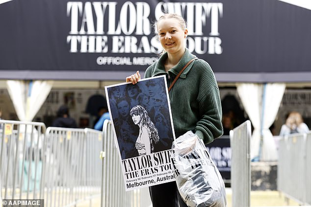 Meanwhile, eager Swifties have already started queuing at the MCG to get their hands on official Taylor Swift merchandise, days before the star's first show on Friday. (Pictured: a Swiftie holding an official tour sign)