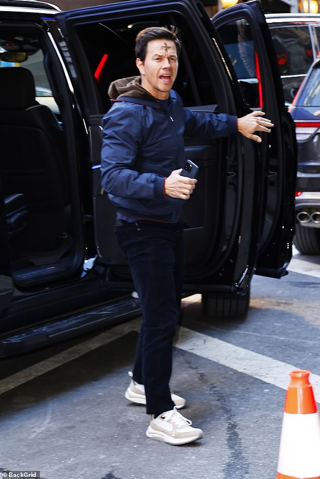 As he entered the studio, the father of four wore a navy blue windbreaker, dark wash jeans, and white sneakers.