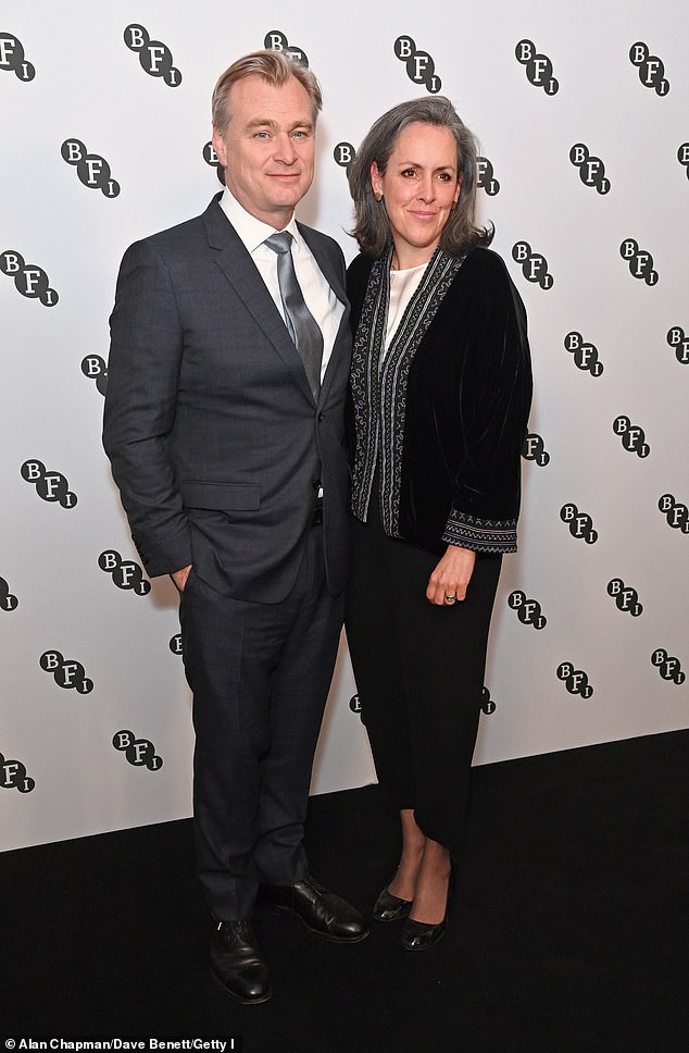 Christopher wore a dark gray suit as he posed for the cameras alongside his wife Emma Thomas.