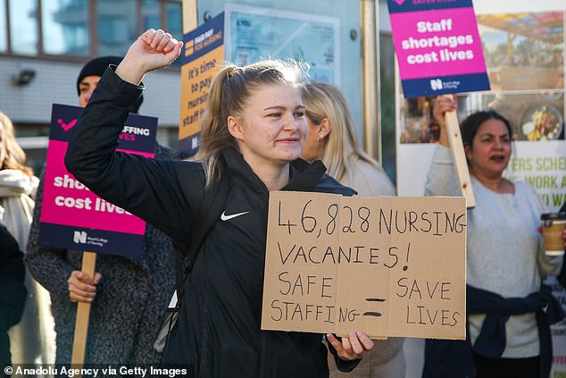 The NHS is battling a shortage of 12,000 hospital doctors and more than 50,000 nurses and midwives amid devastating strikes. Pictured: A nurse holds a banner as a member of the Royal College of Nursing picket line outside St Thomas' Hospital in Westminster on February 6.