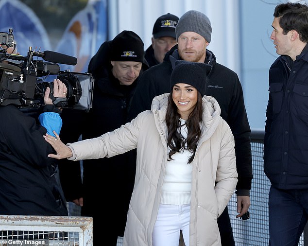 A film crew was seen joining the Sussexes as they arrived for a day of sit-skiing, with the Duchess rubbing the cameraman's arm as they passed.