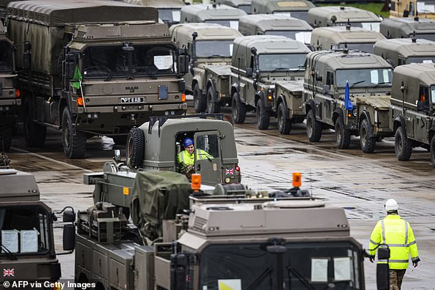 Military vehicles, including trucks and support vehicles, are loaded onto cargo ships bound for Europe.