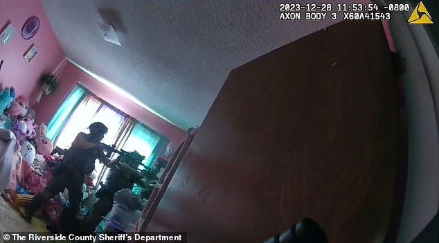 Two officers are seen pointing their guns at Gambill after he was discovered on top of the closet.