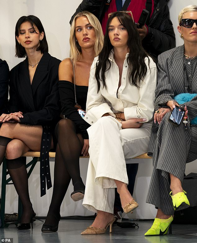 Lottie and Daisy were sitting close together. Lottie was wearing a black off-the-shoulder mini dress and Daisy was wearing an off-white linen suit.