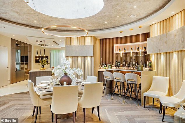 The central dining table is surrounded by a bar area and leads into the modern kitchen.