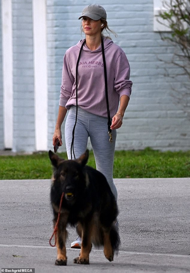 She wore a faded purple Gaia Herbs hoodie and pulled a gray peaked cap over her long blonde hair while out with her beloved dog on Friday in the town of Surfside.