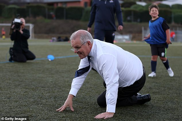The Prime Minister took to the field in his formal shoes and tie to kick the soccer ball impromptu (pictured after the trip)