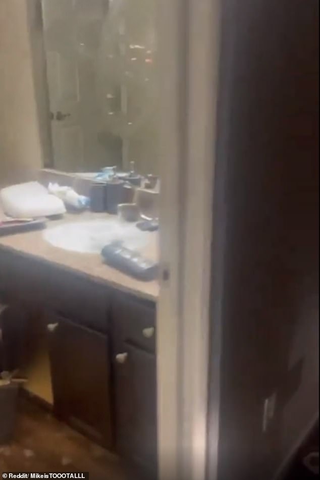 There is product smeared all over the mirror, bathroom sink and countertop, and one of the cabinet doors has also been ripped off and is lying on the floor.