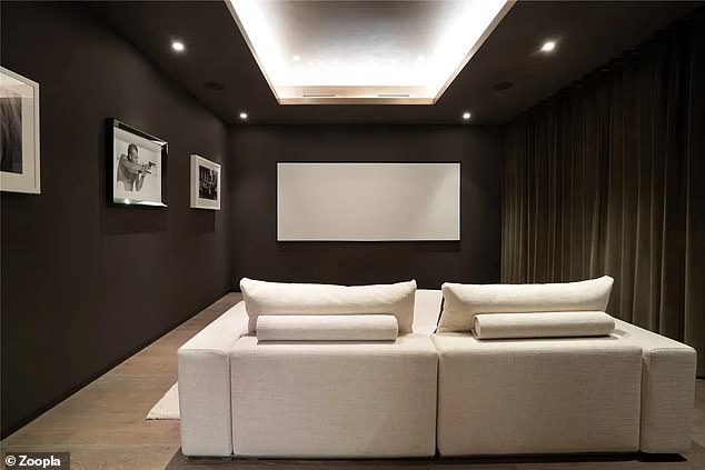 There is a beautiful cinema room with comfortable seating and some spotlights on the ceiling.