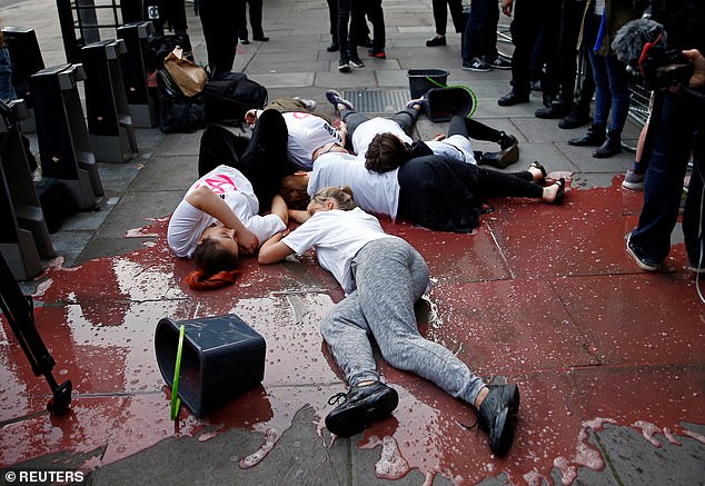 Five members of Extinction Rebellion lying on the 'blood'-soaked pavement in front of press photographers in 2019