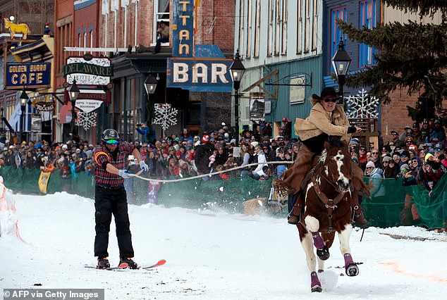 Rider Janelle Urista drags skier Darrin Anderson down Harrison Avenue during the 75th annual Leadville Ski Joring weekend competition in Leadville, Colorado, on March 4, 2023.