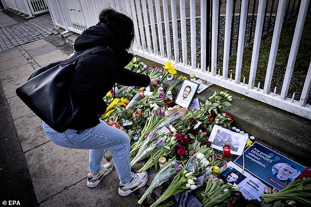 A woman places a flower in front of the Russian embassy in Denmark