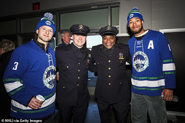 Zac Jones and K'Andre Miller of the Rangers pose with members of the FDNY and NYPD