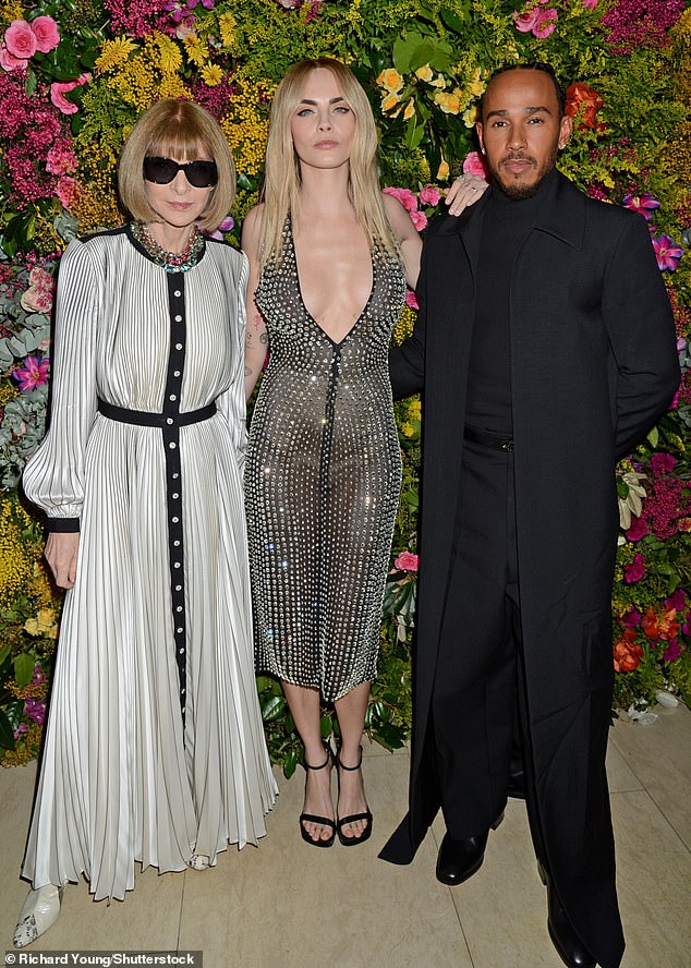 Lewis cut a stylish figure in a black ensemble complete with a long coat, while Anna looked glamorous in a black and white striped dress and sunglasses.