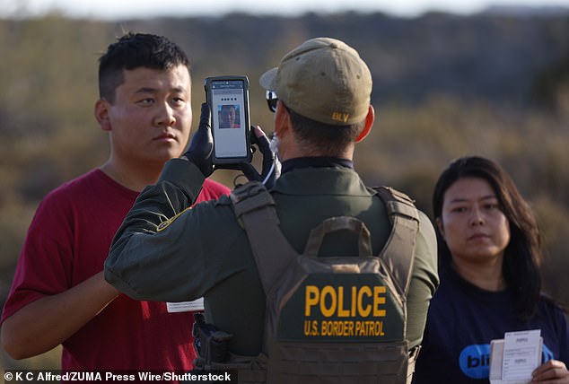 A Chinese migrant seeking asylum holds his passport and documents while being photographed by a US Border Patrol in December 2023.