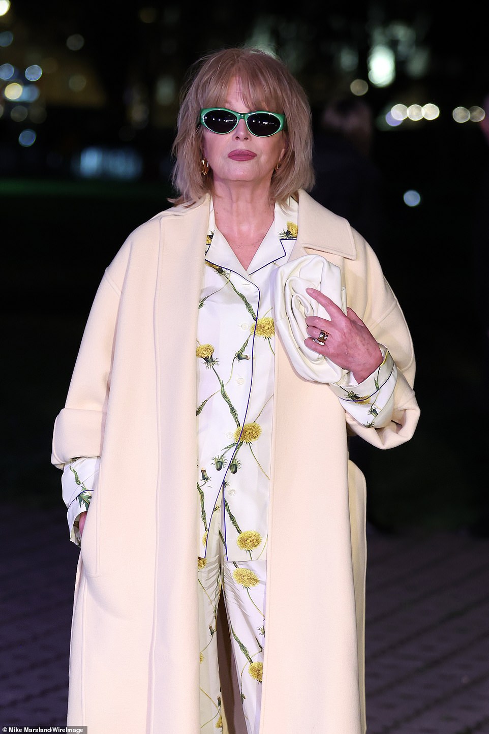 She layered a cream wool coat over an elegant floral silk ensemble that featured an oversized shirt and wide-leg pants.