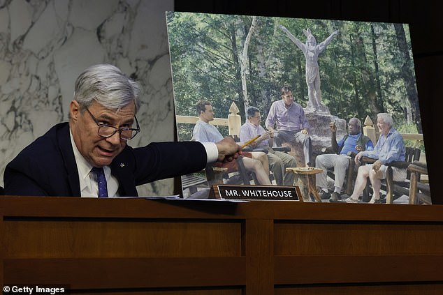Democratic Senator Sheldon Whitehouse displays a painting of Clarence Thomas (second from right) and Harlan Crow (right) meeting at Crow's Adirondacks resort, Camp Topridge. The painting is on display at the New York property.