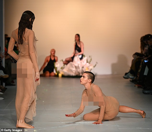 In an unusual performance, one model sat on the floor while looking directly at another model as she stood up.